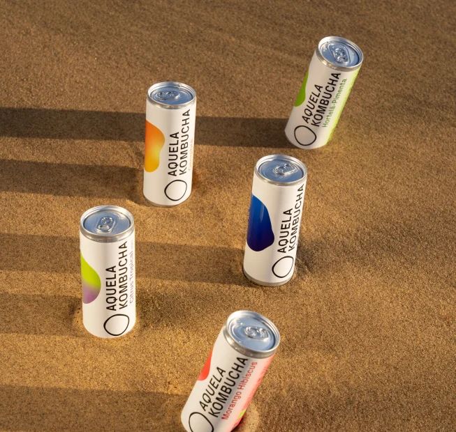 Latas Aquela Kombucha de 25 cl na areia