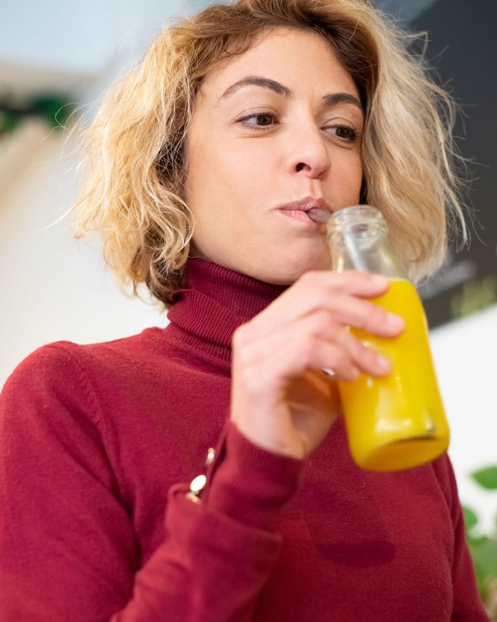 Mulher a beber de uma pequena garrafa de vidro